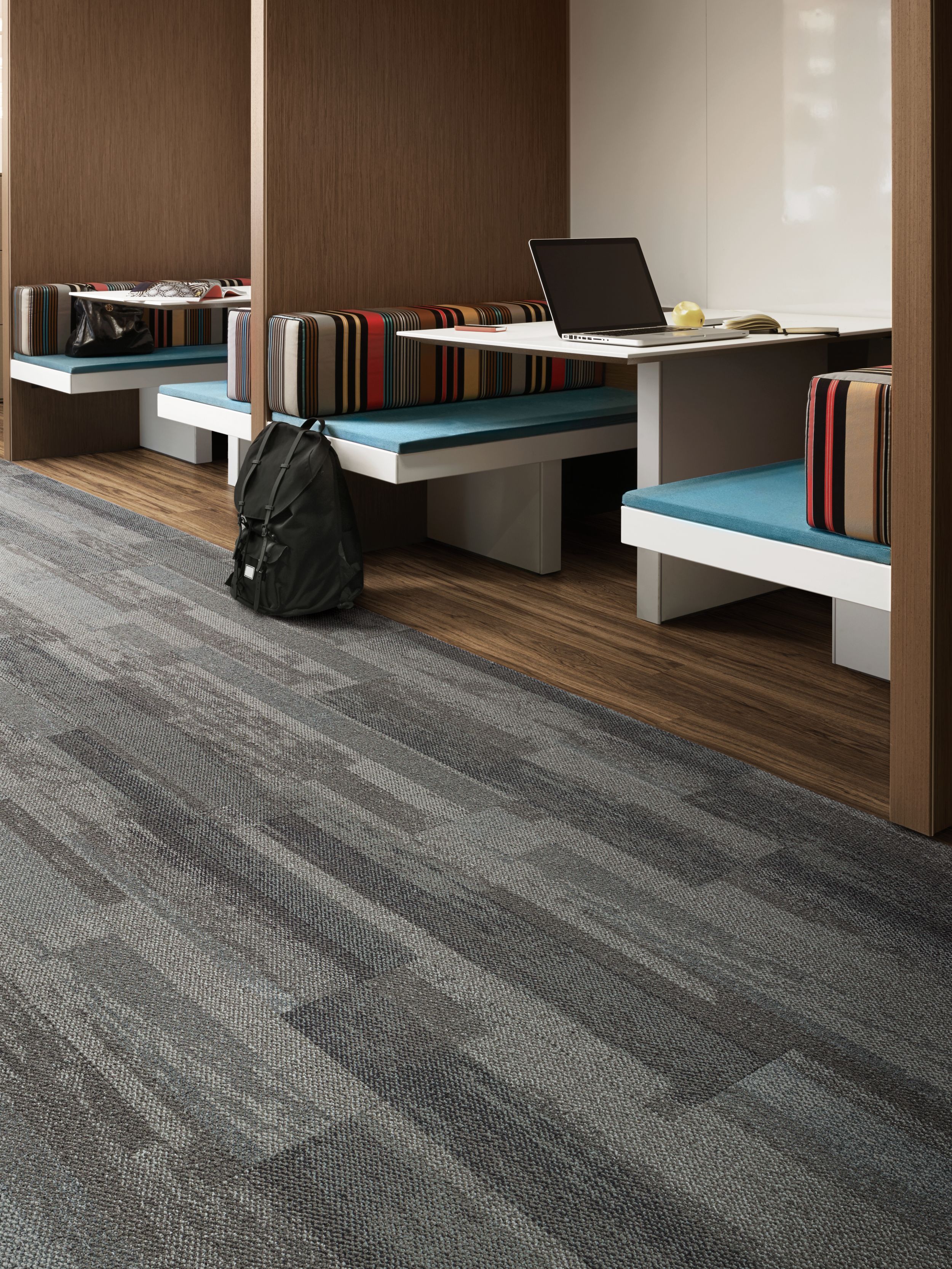 Interface Naturally Weathered plank carpet tile and Natural Woodgrains LVT in office with laptop and backpack in booth seating imagen número 6